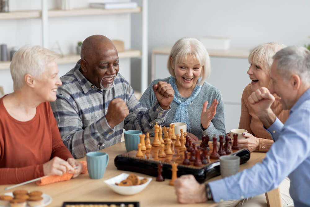 emotional multiethnic group of senior people playing a game of chess