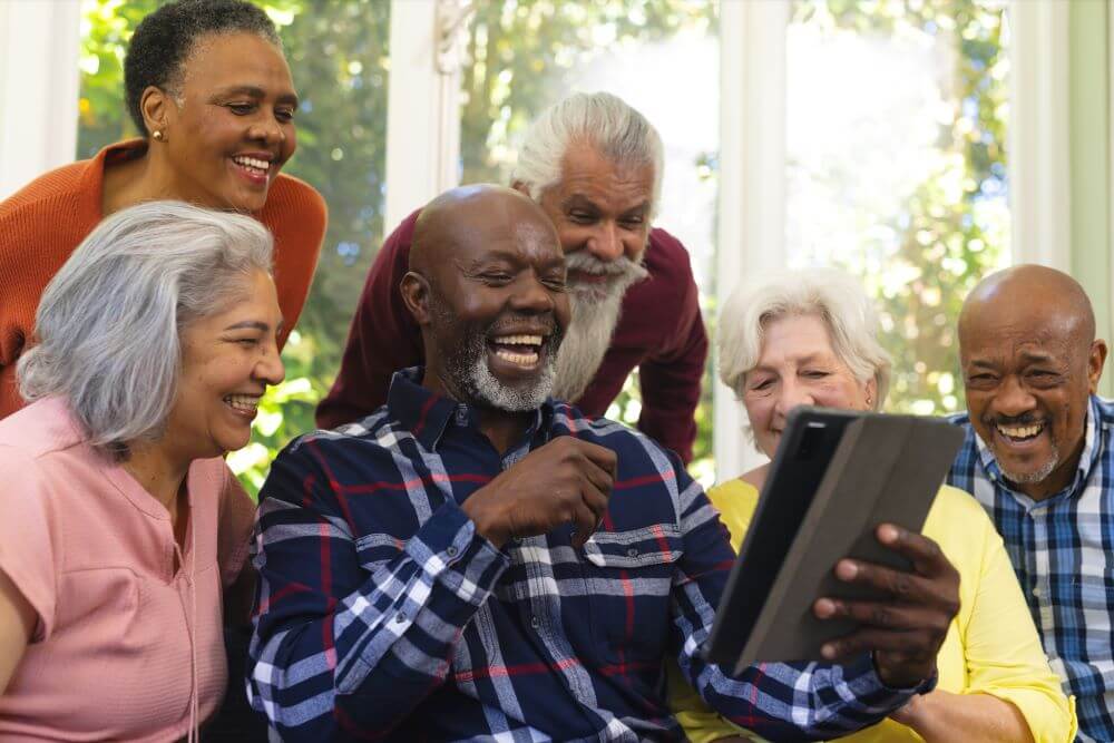 Photo of a group of seniors looking at a tablet and laughing.